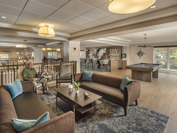 A cozy and modern lounge area featuring comfortable sofas, a pool table, and stylish lighting.