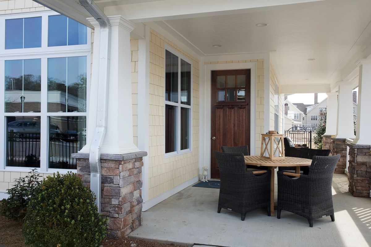 A cozy front porch with a wooden door and outdoor seating arrangement.