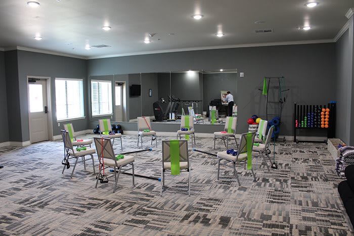 An empty exercise room with chairs arranged in a circle, equipped with fitness accessories.