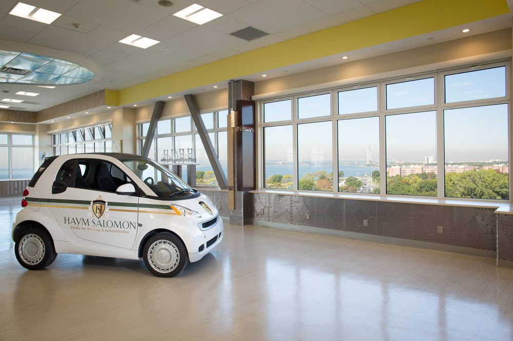 A small hospital vehicle parked inside a modern building with large windows.