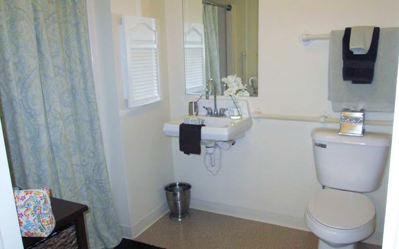A clean and tidy bathroom featuring a sink with a mirror, toiletries, and a towel.
