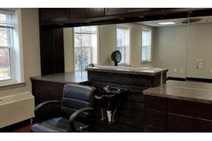 A modern hair salon featuring a sleek barber chair and large mirrors.