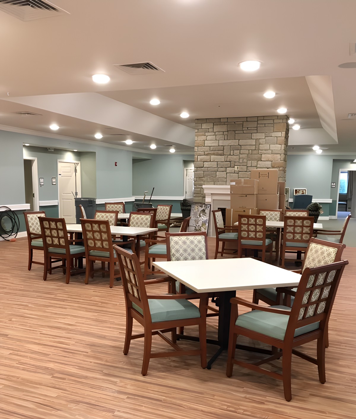 An empty dining area with wooden flooring and neatly arranged tables and chairs.