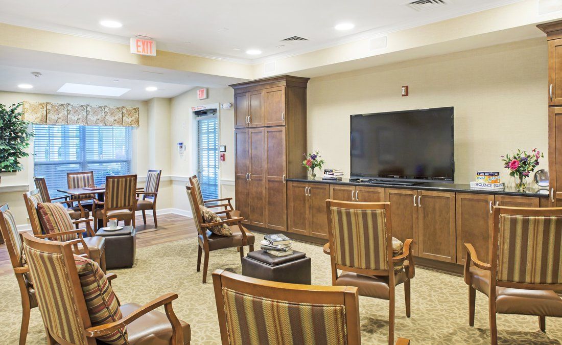 A cozy seating area with wooden chairs and a large television.