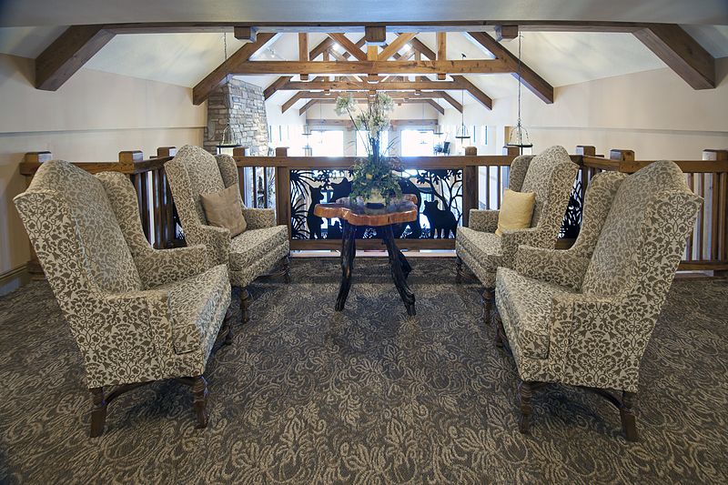 A cozy seating area featuring armchairs and a central table with wooden beams overhead.