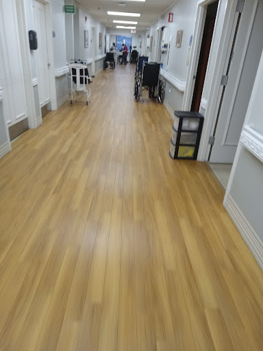 A view of a well-lit hallway with wooden flooring and furniture along the sides.
