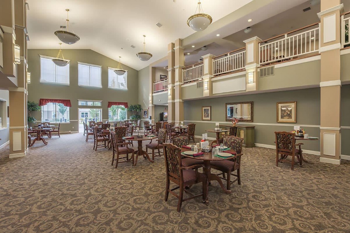 An elegant dining room with high ceilings and neatly arranged tables and chairs.