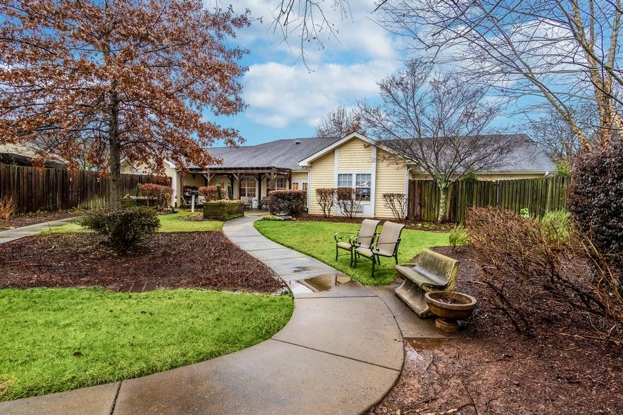 A serene garden path leads to a cozy house surrounded by greenery.