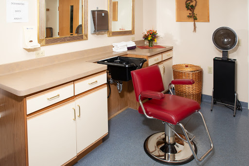A modern hair salon featuring a red styling chair, mirrors, and clean countertops.