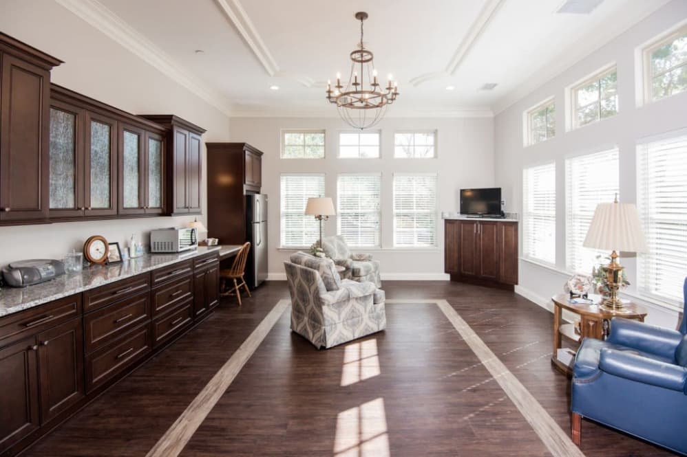 A modern open-concept living room and kitchen with hardwood floors and ample natural light.