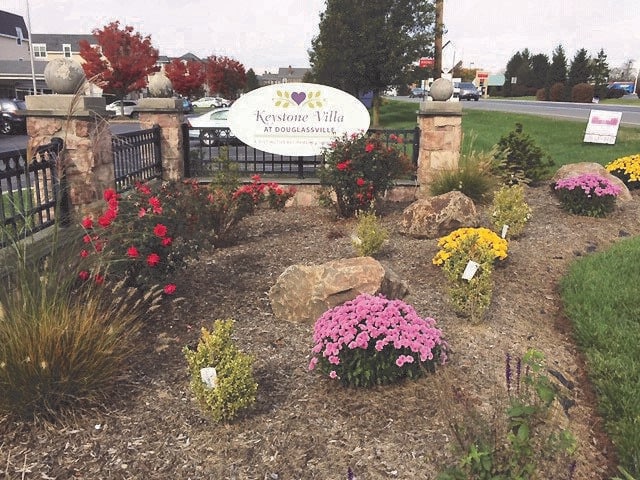 A landscaped garden with colorful flowers and a welcome sign.