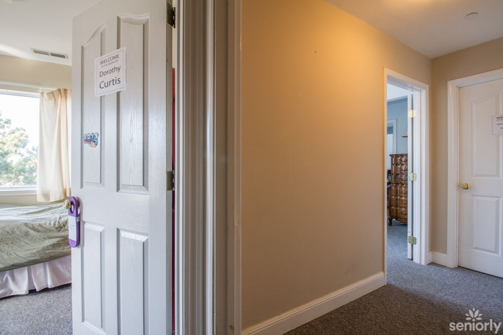 A carpeted hallway with an open door leading to another room.