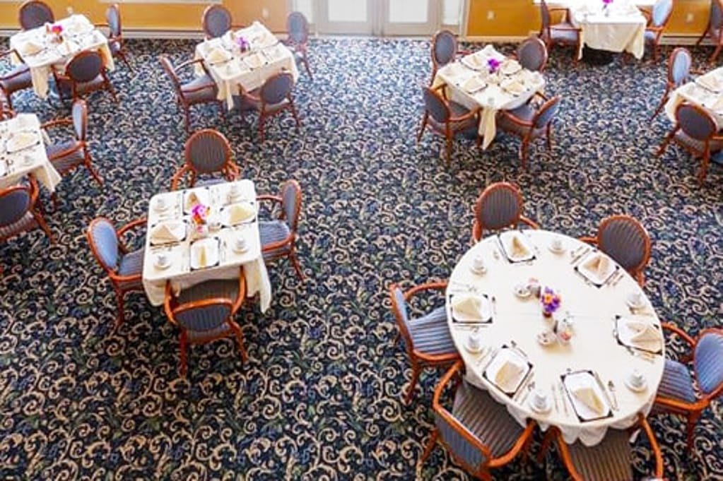 Aerial view of a neatly arranged dining room with several tables and chairs, set for guests.