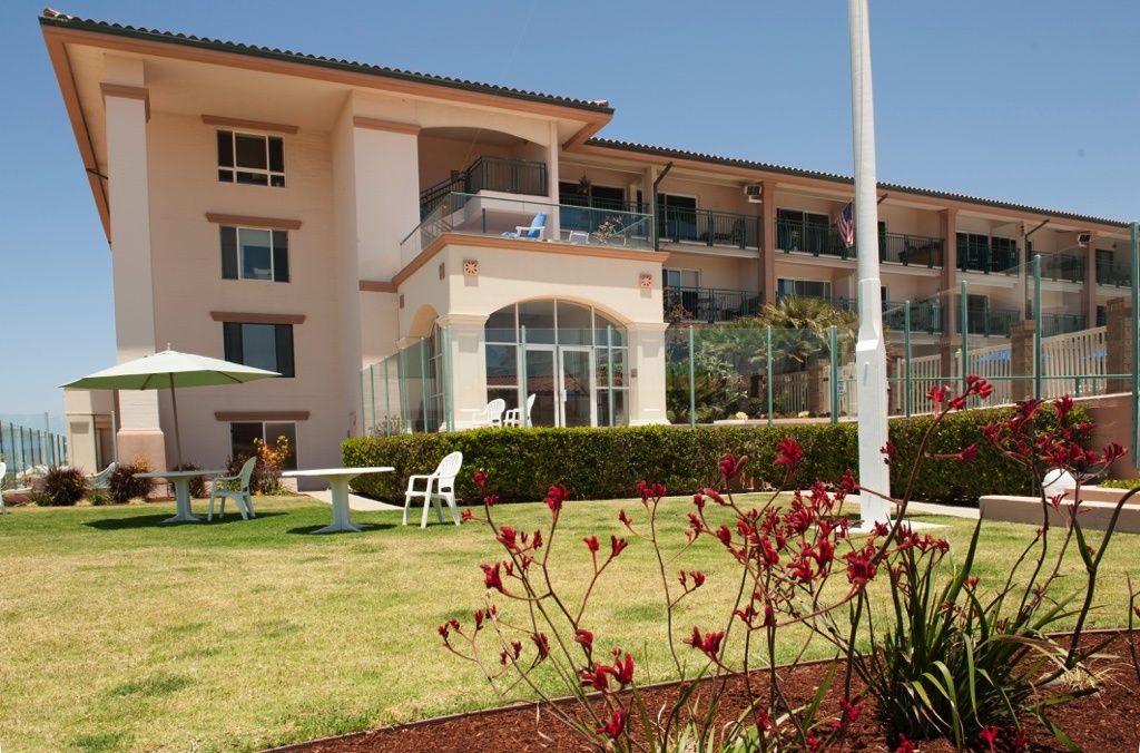 A well-maintained garden in front of a multi-story building with large windows and balconies.