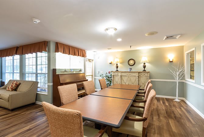 A well-lit dining or meeting area featuring a long table and comfortable chairs, decorated with elegant lighting and furnishings.