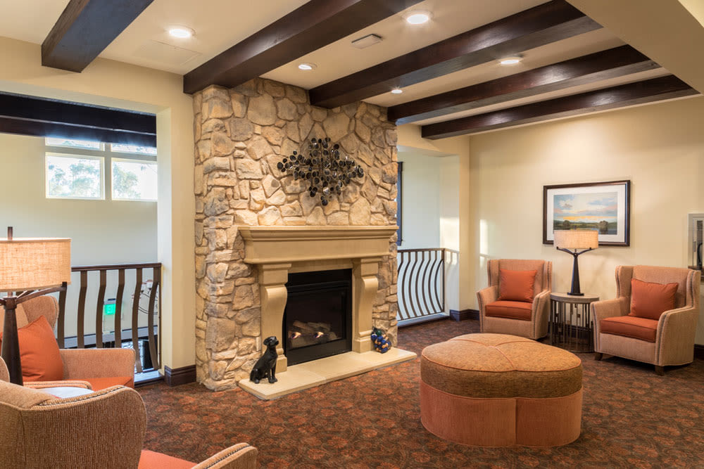 A cozy living room featuring a stone fireplace, armchairs, and stylish decor.