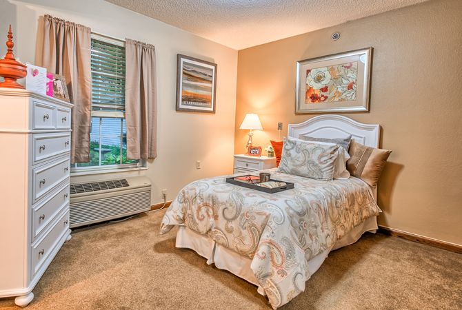 A cozy bedroom with warm lighting, featuring a neatly made bed and elegant decor.