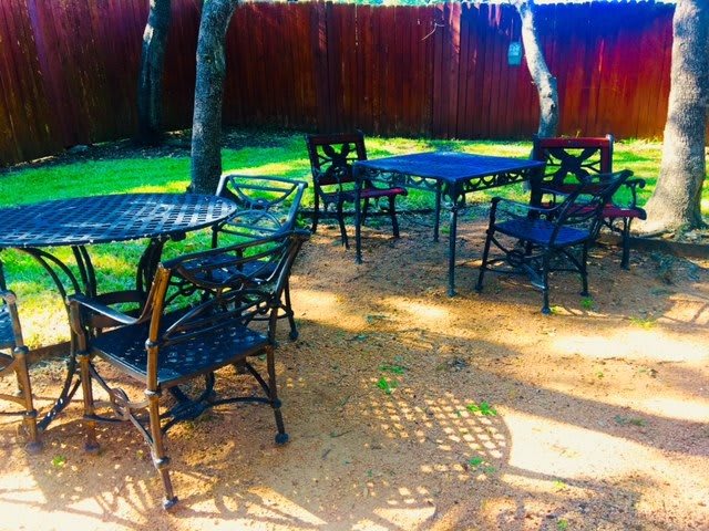 A sunny outdoor patio with tables and chairs set in a garden.