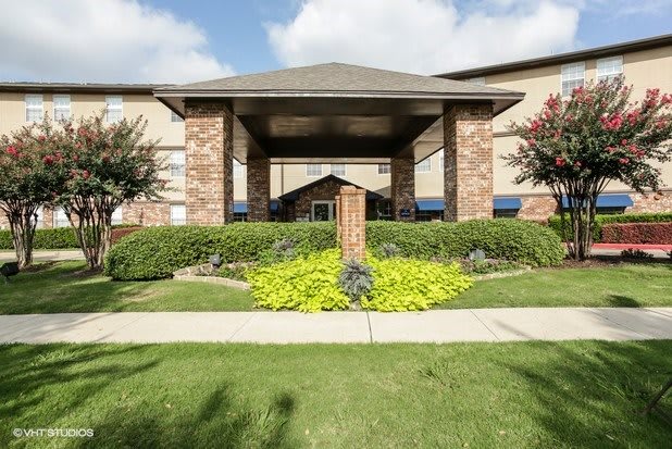 A residential building with a landscaped entrance and clear skies.