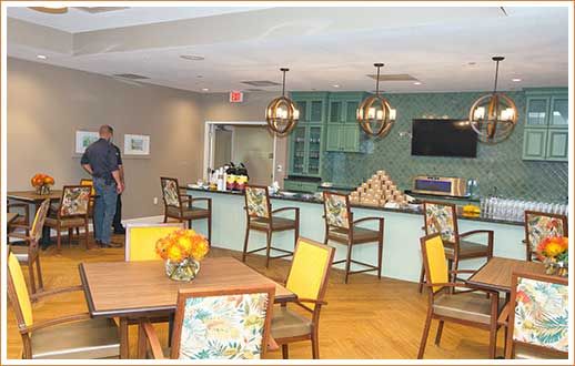 A modern kitchen and dining area featuring a bar counter with chairs, stylish lighting fixtures, and a television on the wall.
