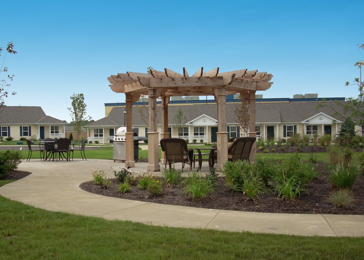 A landscaped garden with a wooden pergola and outdoor seating.