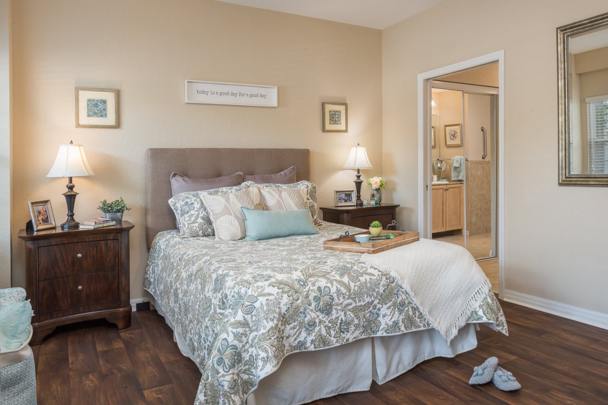A cozy bedroom with a neatly made bed, nightstands, and soft lighting.