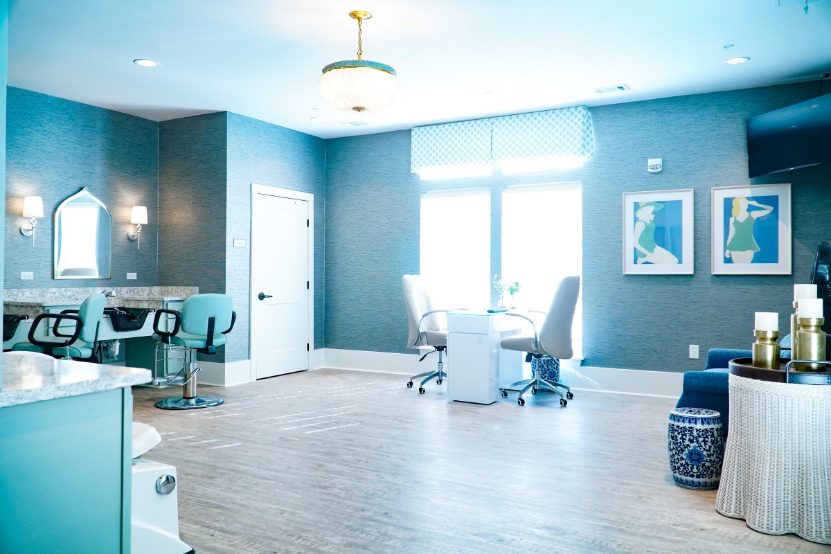 A modern and bright office interior with blue walls, featuring desks and chairs by a large window.