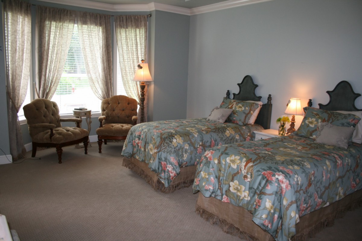 A cozy bedroom with twin beds, floral bedding, and elegant decor.