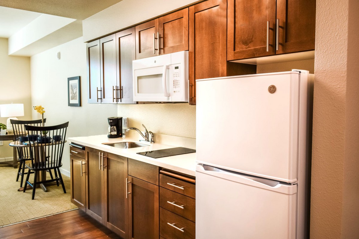 A modern kitchen with wooden cabinets, a microwave, and a refrigerator.