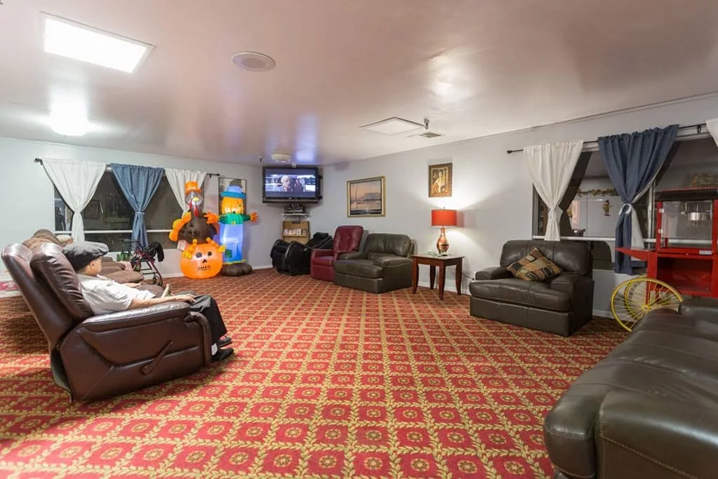 A cozy lounge area with multiple sofas, a television, and a patterned carpet.