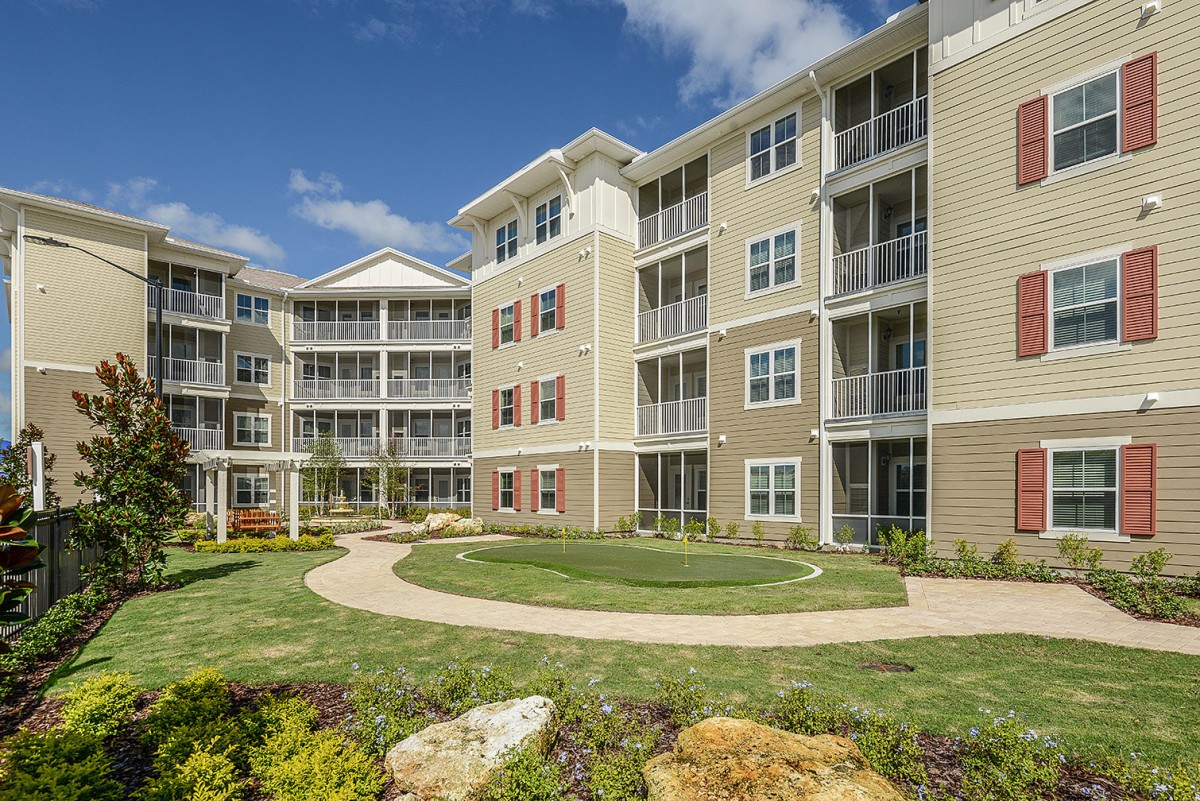 A modern residential apartment complex with well-maintained landscaping and multiple balconies.