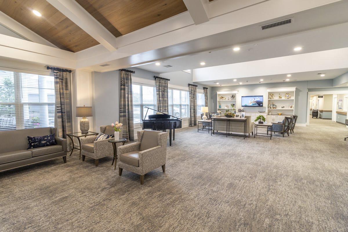 A spacious and elegantly decorated lounge with comfortable seating and a grand piano.