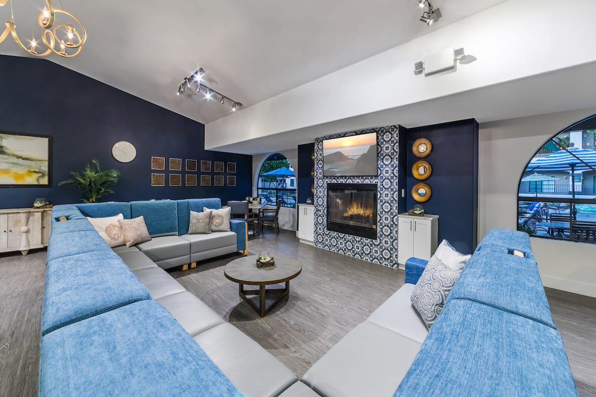 A modern living room with a blue color scheme, featuring a spacious seating area and a decorative fireplace.