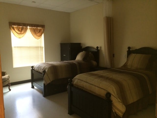 A cozy bedroom with two twin beds and a window adorned with curtains.