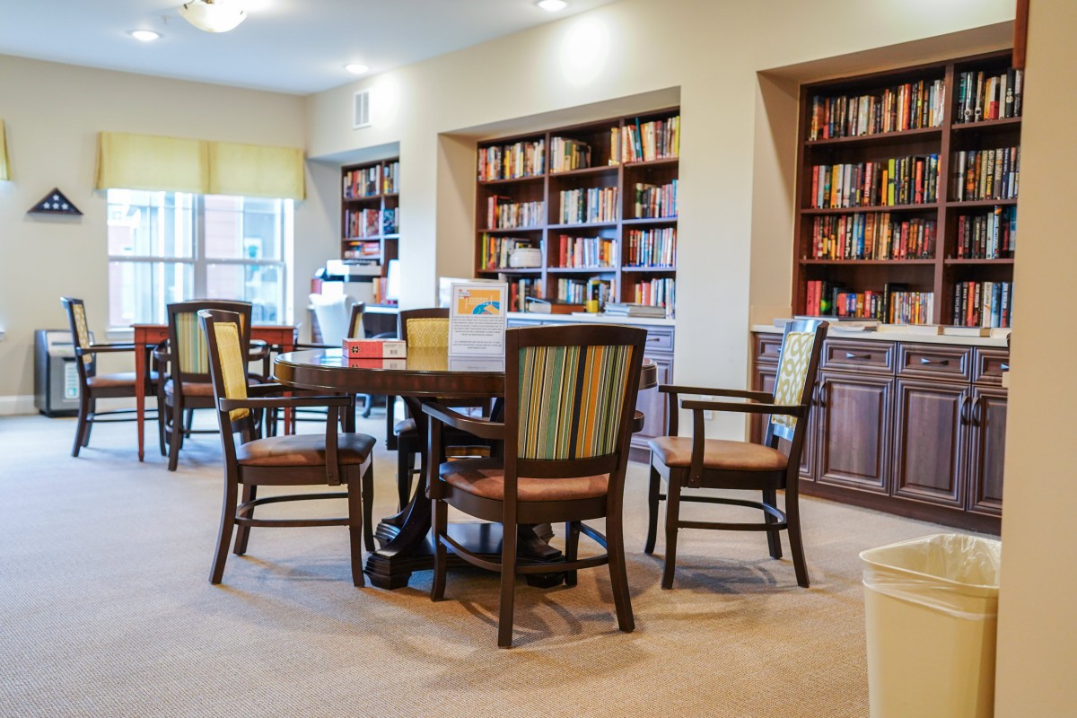 A cozy library reading area with a table and chairs surrounded by bookshelves.