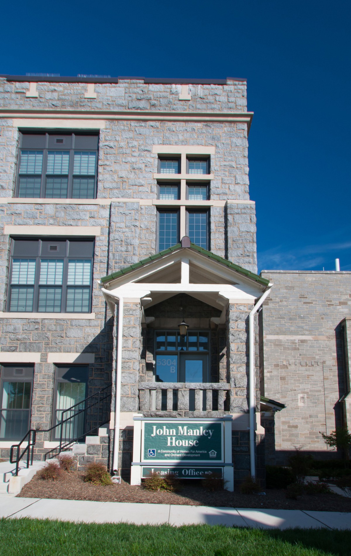 A historic stone building with a prominent entrance and a small balcony under a clear blue sky.