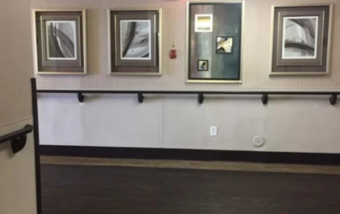A hallway featuring several framed paintings and a handrail.