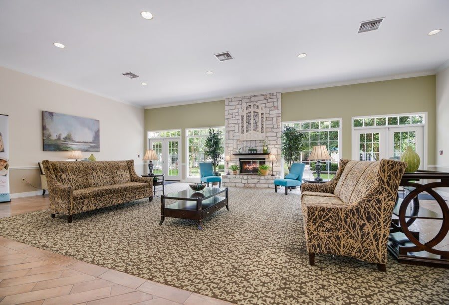 A spacious living room with elegant furniture, featuring a central fireplace and large windows.