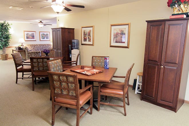 A cozy dining area featuring a wooden table and chairs, adorned with framed artwork on the walls and a water dispenser nearby.