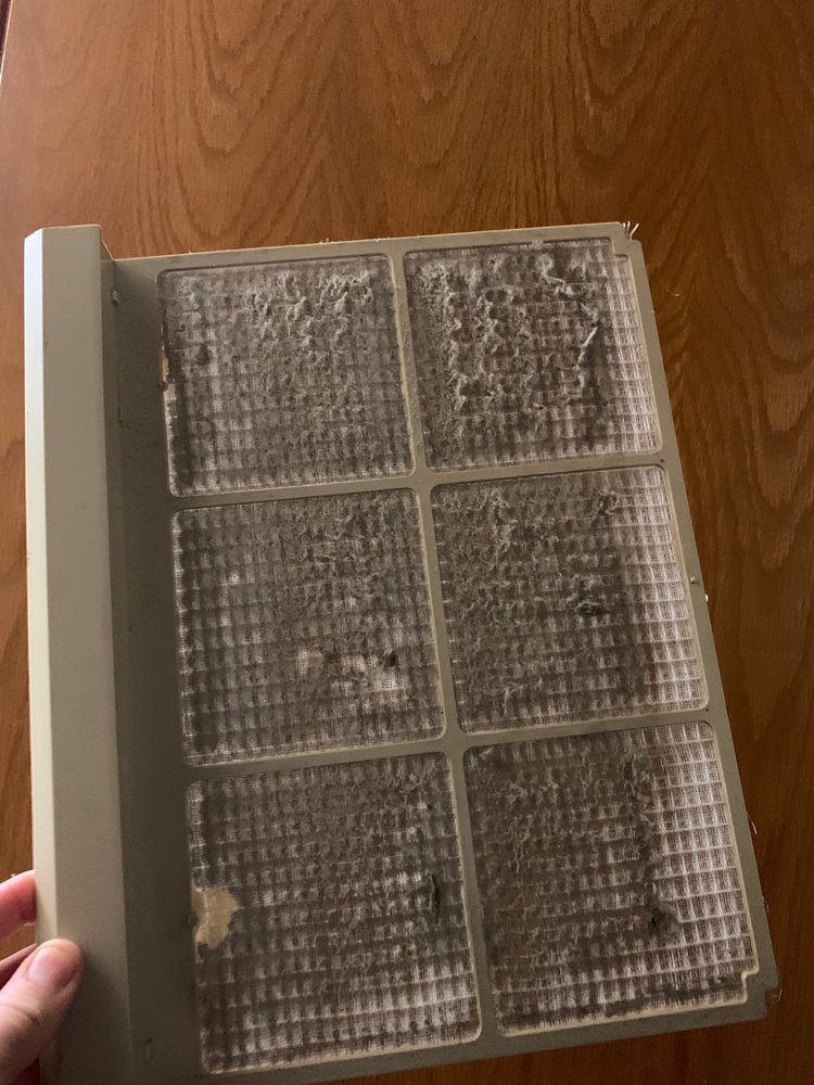 A dirty air filter needing replacement or cleaning, showing accumulated dust and debris.