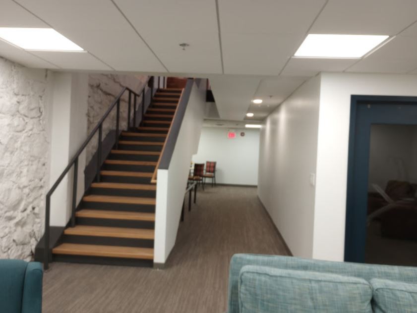 A modern office hallway with a staircase leading to an upper level.