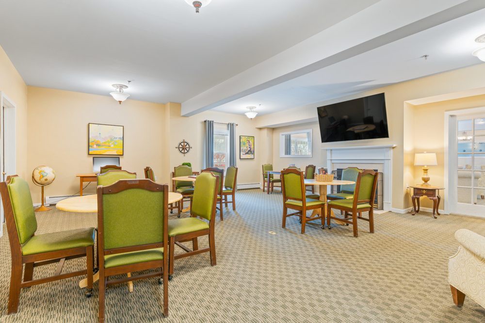 A spacious dining room with tables, chairs, and a wall-mounted television.