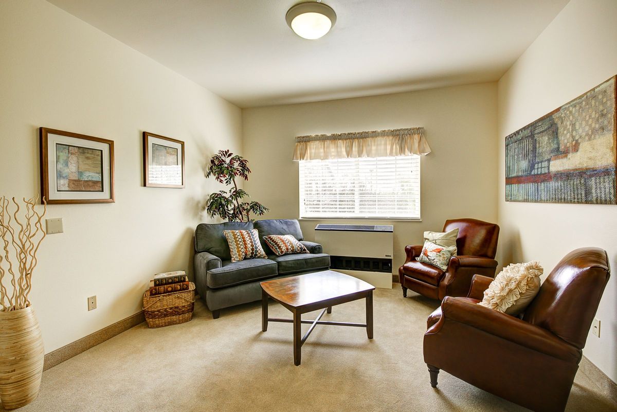 A cozy living room with a couch, two armchairs, and a coffee table.