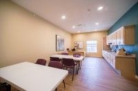 A well-lit kitchen with tables and chairs arranged for dining or meetings.