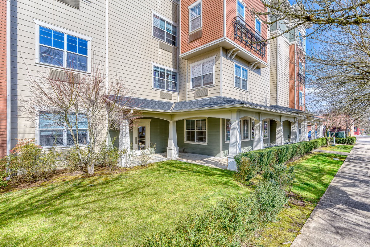 A sunny view of an apartment building with well-maintained landscaping.