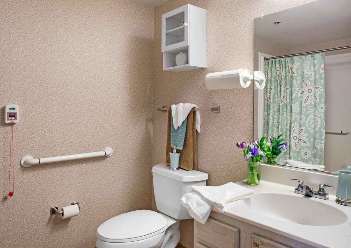 A clean and organized bathroom with a toilet, sink, mirror, and fresh flowers adding a touch of decor.