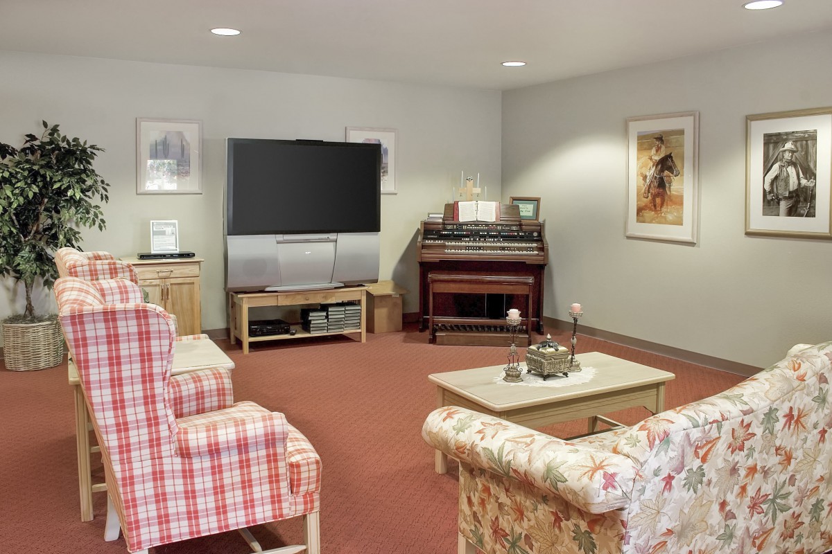 A cozy living room with a television, piano, and comfortable seating arrangements.