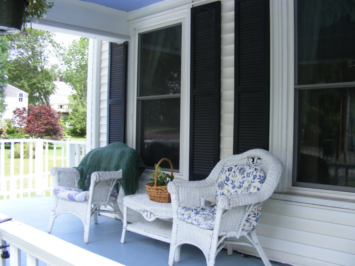 A cozy porch setup with wicker chairs and plants in a basket.
