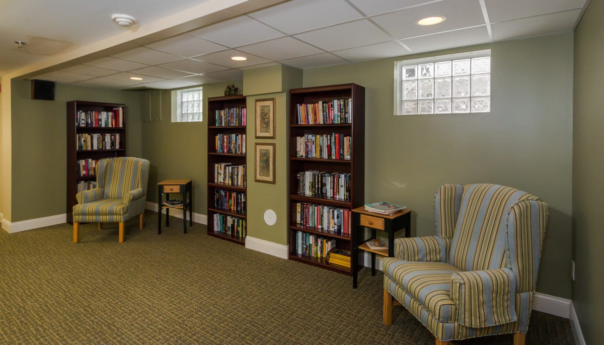 A cozy basement library with bookshelves and armchairs, perfect for reading.