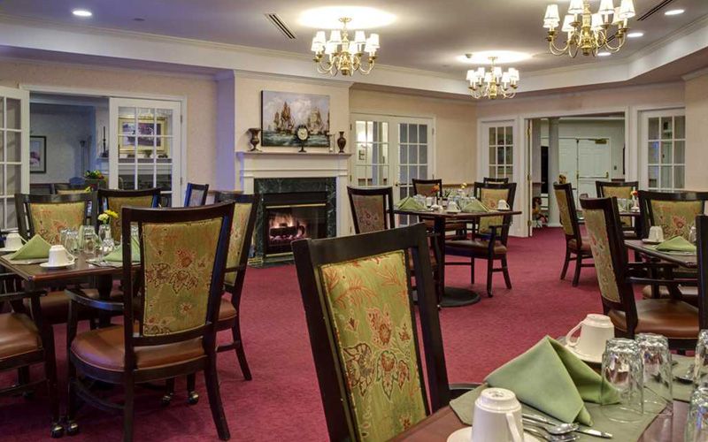 An elegant dining room with a cozy fireplace and multiple tables set for guests.